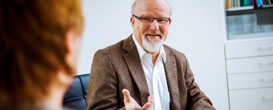 Ein Mann mit Brille erklärt einer Person, die am linken Bildrand zu sehen ist etwas.