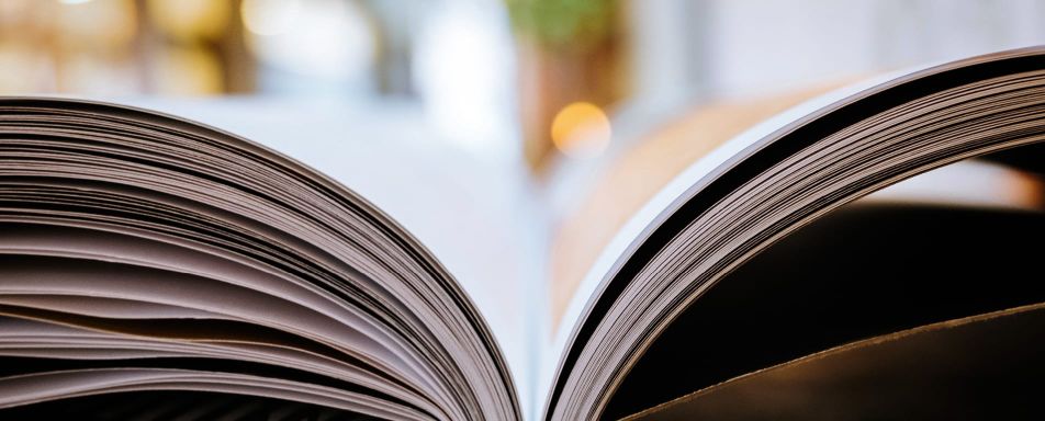 Nahaufnahme eines aufgeschlagenen Buches, das in einem weichen Licht liegt und Details der Buchseiten zeigt.